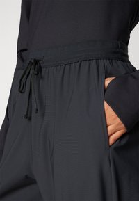 Mørke, letvægts joggers har en elastisk talje med snører, sidelommer og et glat, struktureret stof.
