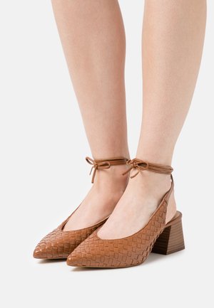 Talons en cuir tressé marron avec un bout pointu, une ouverture à l'arrière et des lacets à la cheville. Des talons en bois épais et une texture lisse complètent le design.