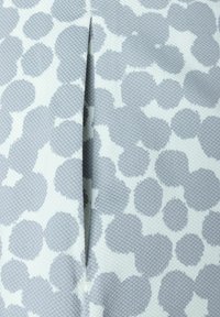 Harmaa teksturoidun kankaan pinta, jossa on abstrakti pilkkukuosi eri harmaan sävyissä, näkyvällä sauma- tai laskoskohdalla.