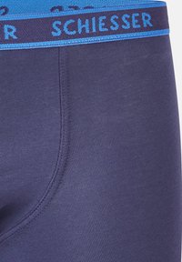 Mörkblå stretchbomull boxershorts med en texturerad yta och ett kontrasterande blått midjeband med varumärket "Schiesser" i vitt.