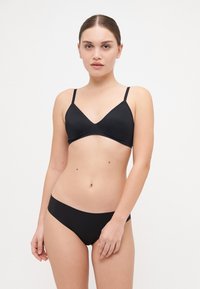 Fekete bikini szett, V-nyakú bralette-tel, állítható pántokkal és illeszkedő, alacsony derekú alsóval. Simított, rugalmas anyagból készült.