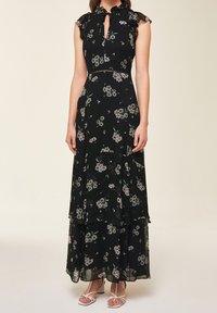 Svart blommig maxiklänning med volangärmar, nyckelhålsutskärning och lager av volanger. Har ett blommigt mönster i ljusa färger.