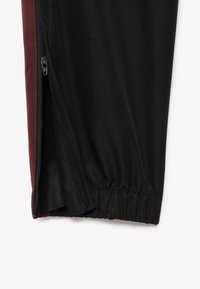 Svarta och vinröda sportshorts med dragkedja i sidofickan, elastisk midja och strukturerad tyg. Fokusera på funktionella design detaljer.