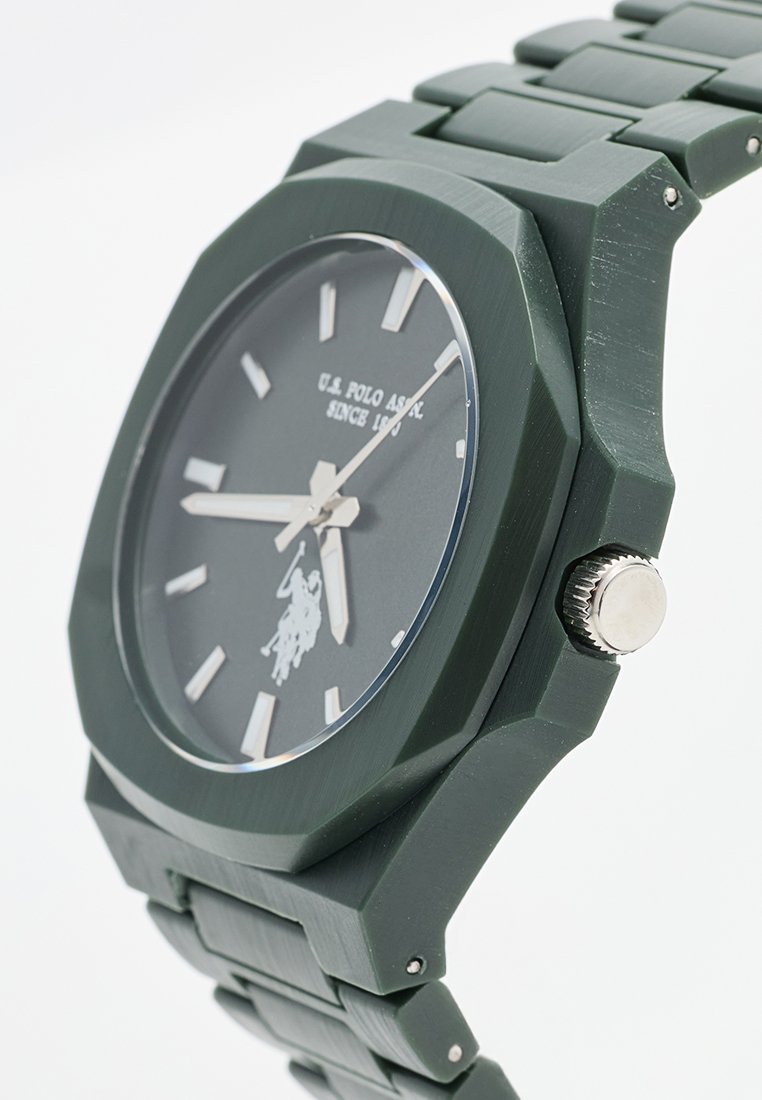 Reloj de silicona verde con caja octagonal, esfera gris, marcadores plateados y detalle del logotipo. Presenta una correa texturizada y corona de acero inoxidable.