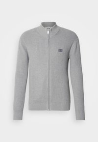 Maglione grigio a coste con zip, dotato di colletto alto e polsini aderenti. Presenta una piccola patch con logo sul lato sinistro del petto e una zip liscia.