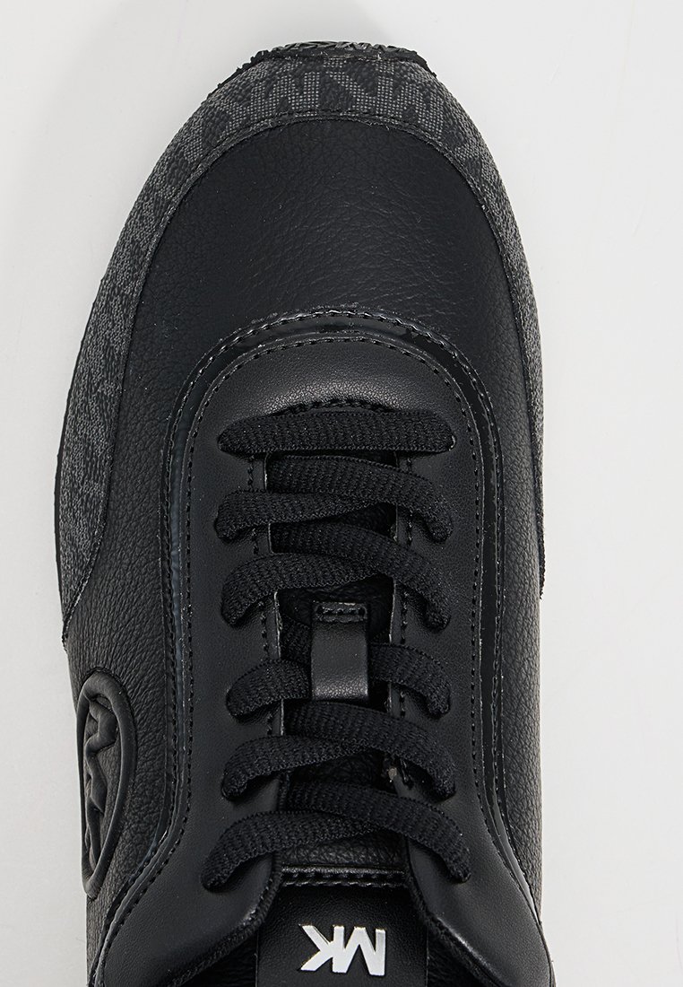 Zwarte leren en stoffen sneaker met zwarte veters, gestructureerde zool en wit "MK" logo op de tong.