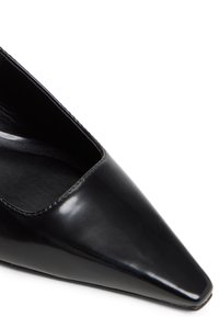 Zapato de charol negro de punta afilada con un escote bajo y un acabado suave y brillante. Presenta una silueta elegante y costuras mínimas.