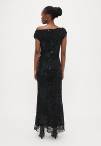 Melna vakarkleita ar spīdīga fliteru apdari, plecus atsedzošs dizains, ziedu raksts un plūstošs audums, ar oderētu apakšmali un pieguļošu siluetu.