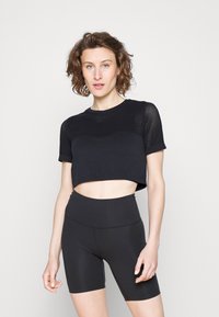 Top cropped preto com um design de malha texturizada, combinado com calções pretos de cintura alta, ambos feitos de material elástico.