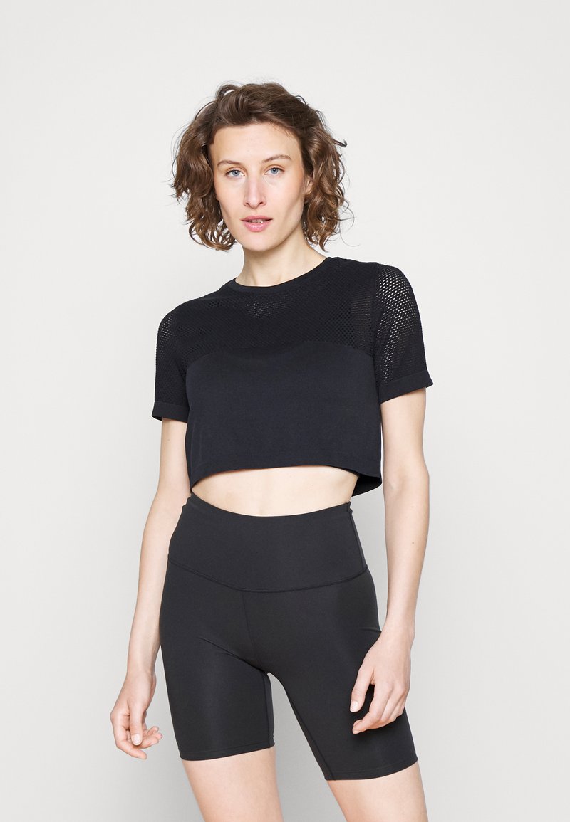 Top cropped preto com um design de malha texturizada, combinado com calções pretos de cintura alta, ambos feitos de material elástico.