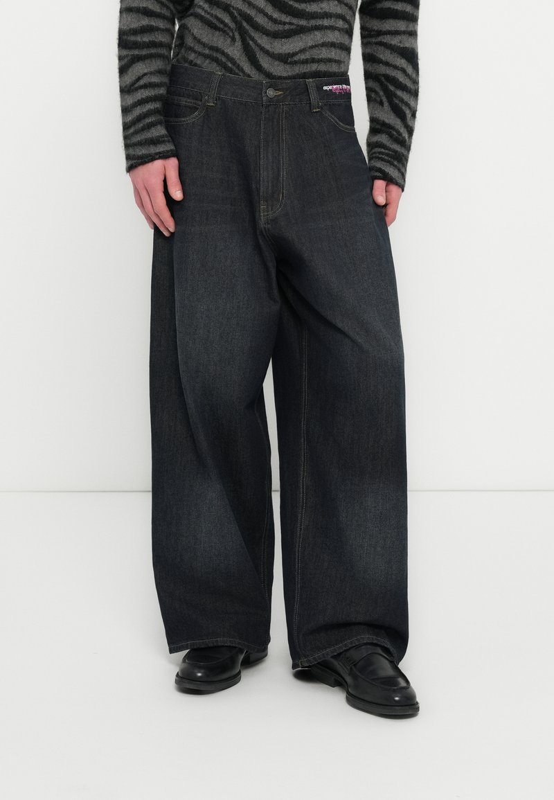 Μαύρο τζιν παντελόνι με φαρδιά μπατζάκια και ψηλή μέση, με χρυσές ραφές, εμπρόσθιες τσέπες και ετικέτα με το λογότυπο στη μέση.