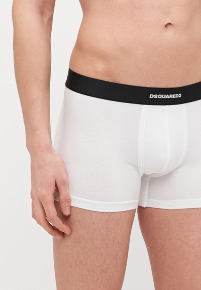 Weiße Baumwoll-Boxershorts mit einem schwarzen elastischen Bündchen, das das "DSQUARED2"-Logo zeigt. Glatte Textur und figurbetontes Design.