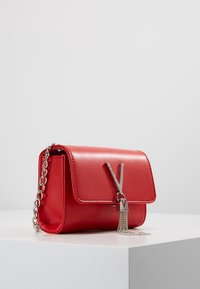 Borsa in finta pelle rossa con chiusura a pattina, tracolla in catena argentata e un zipper decorativo con un accento di gemme.