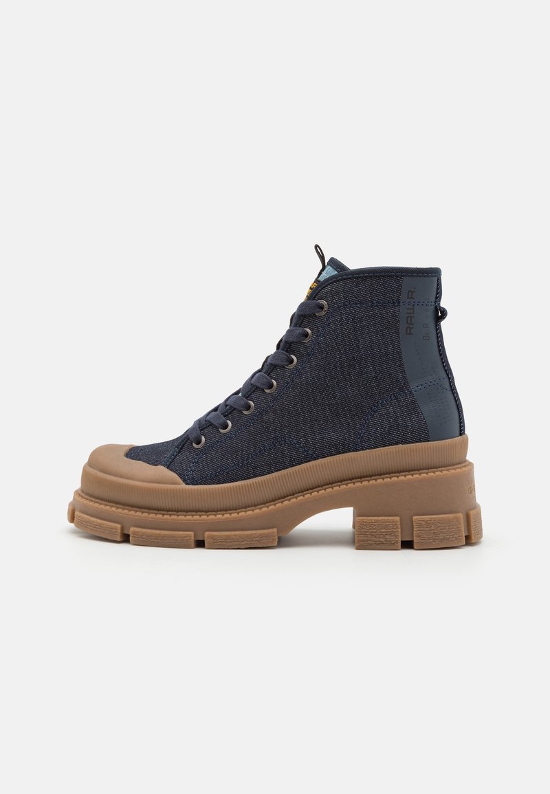 Botas altas de denim azul oscuro con suela y punta de goma clara. Presentan cordones redondos y un logo en el tobillo.