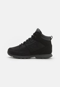 Zapatillas negras de caña alta con una parte superior de cuero suave y malla, suela texturizada, puntera redonda y logotipo visible en el lateral.