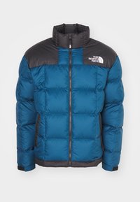 Blå og sort polstret jakke med frontlynlås, høj krave, sidelommer og "The North Face" logo på øverste venstre bryst.