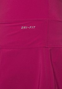 Top deportivo fucsia que cuenta con tecnología DRI-FIT que expulsa la humedad. Tejido suave con un diseño sin costuras y detalles de costura sutiles.
