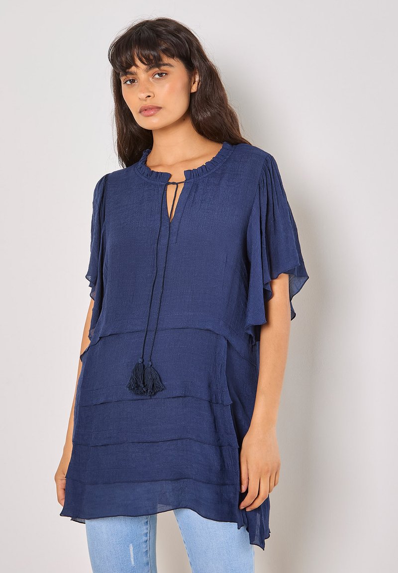 Navyblaue Tunika mit rundem Ausschnitt, Schlüsselbein-Ausschnitt und Quastenzug. Leichter Stoff mit geschichtetem Design und schwingenden Ärmeln.