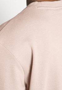 Camiseta de algodón rosa claro con un escote de cuello redondo y diseño de manga corta, con textura acanalada y sutiles detalles de costura.