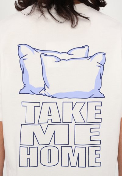 Witte T-shirt met een grafisch ontwerp van twee lichtblauwe kussens boven de tekst "NEEM ME MEE NAAR HUIS" in vetgedrukte blauwe letters.