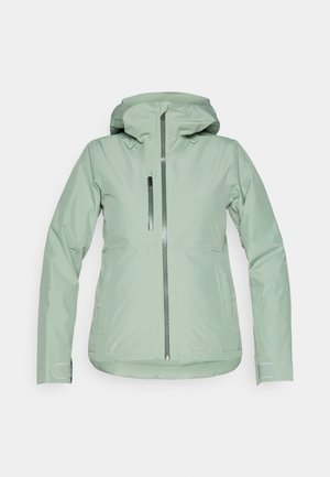 Chaqueta impermeable verde claro con cierre de cremallera en la parte delantera, capucha ajustable y bolsillos laterales; textura suave y diseño ajustado.
