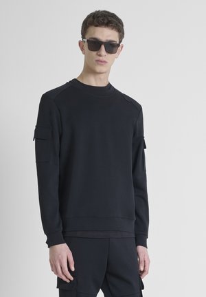 Sweatshirt noir en mélange de coton, avec manches longues, col rond et deux poches avant avec fermetures à rabat.