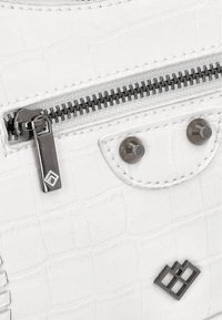 Hvid håndtaske med krokodillepræg, der har sølvfarvet hardware, en markant lynlås og nitter. Fremtrædende rektangulært logodetail foran.
