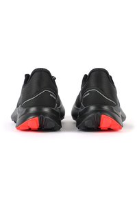 Scarpe da corsa nere con una parte superiore testurizzata, dotate di una intersuola nera e accenti di suola esterna rossi brillanti, che mettono in mostra un design elegante.