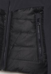Navy jacket section with puffy black insulated lining, featuring a zippered pocket on the right and smooth texture.