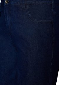 Jeans de mezclilla azul oscuro mostrando el bolsillo delantero, la pretina con botón y detalles de costuras.