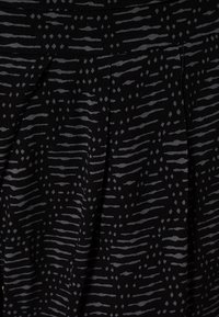 Svart tyg med grå vågiga och diamantmönster, med plisseringar fram för extra struktur och design.