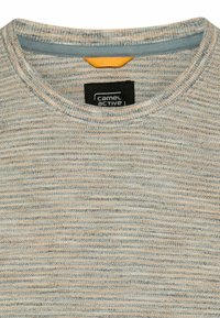 Nærbillede af beige og lyseblå stribet striktrøjes halskant med sort Camel Active-mærke og lille orange stofdetalje inde i kraven.