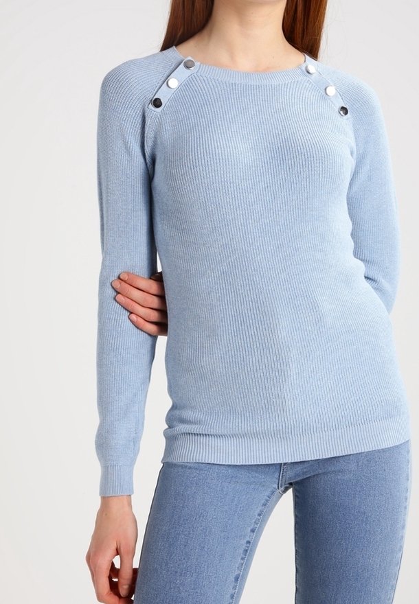 Ljusblå rippad tröja med långa ärmar, prydd med silverfärgade tryckknappar på axlarna och en figurnära silhuett.