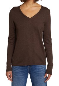 Brązowy sweter w serek wykonany z miękkiej dzianiny, z długimi rękawami i ściągaczami; w zestawie z niebieskimi dżinsami.