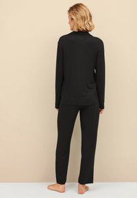 Zwarte lange mouw top en bijpassende broek van zachte stof. Het ontwerp is eenvoudig, met een ontspannen pasvorm en geen zichtbare patronen of accenten.
