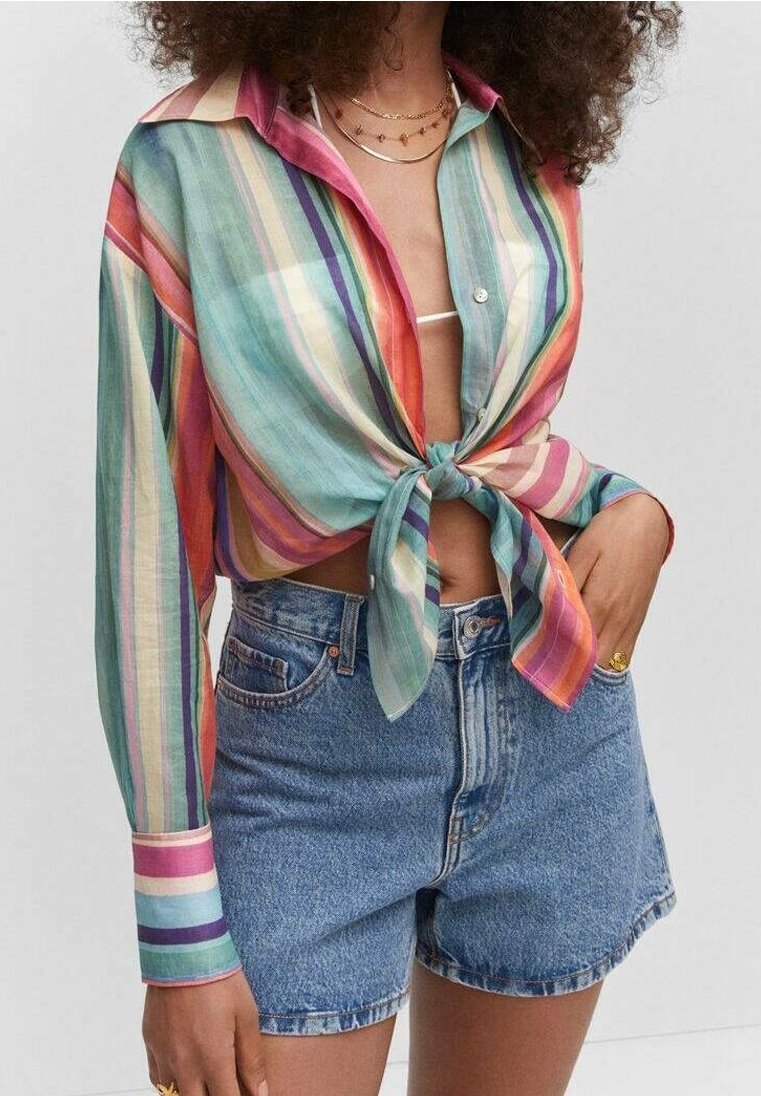 Chemise rayée multicolore à manches longues nouée à la taille, associée à un short en denim taille haute. Tissu texturé et léger.