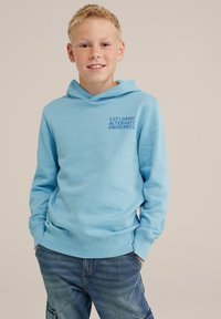 Valkoinen huppari, jossa on resorit hihansuissa, ja jota koristaa rinta-alueella tummansinisellä teksti "TUTKIMASSA ALTERNATIIVISIA UNIVERSUMEITA".