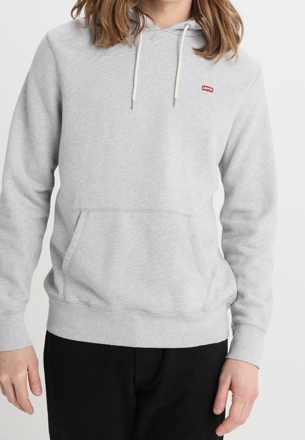 Persona que lleva una sudadera ligera gris de Levi's con bolsillo frontal y capucha con cordón, combinada con pantalones negros.