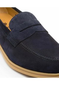 Navyblauer Wildleder-Slipper mit einer flachen Gummisohle, der ein genähtes Akzentband über dem Obermaterial und ein weiches gelbes Innenfutter aufweist.
