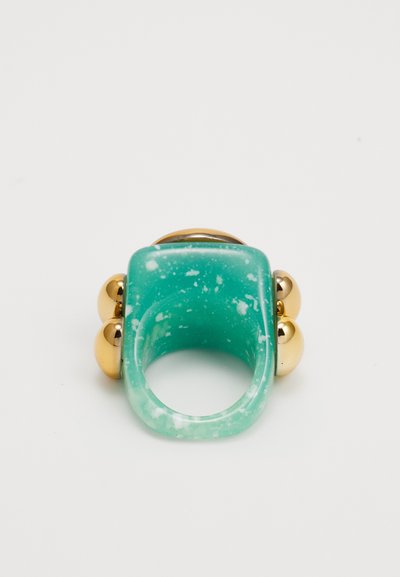A turquoise resin ring featuring a smooth finish, gold metal accents, and two spherical embellishments on either side.