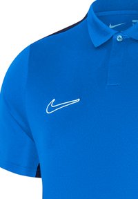 Polo blu realizzato in tessuto morbido, con colletto classico, maniche corte e logo Nike swoosh bianco sul lato sinistro del petto.