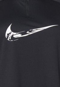 Black athletic top featuring a prominent white Nike swoosh logo. The fabric appears smooth with a slight sheen and minimal seams.