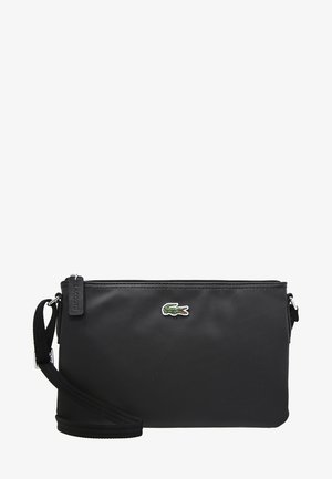 Sac en nylon noir à porter en bandoulière, avec une surface texturée, doté d'un petit logo crocodile vert et rouge, fermeture à zip et bandoulière réglable.