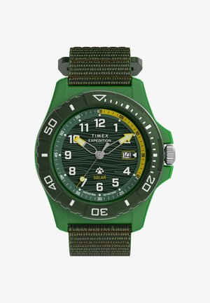 Vihreä Timex Expedition -aurinkokello kangashihnalla, pyörivällä kehyksellä, päivämääränäyttö kello 3 kohdalla ja vedenpitävyys 50 metriin asti.