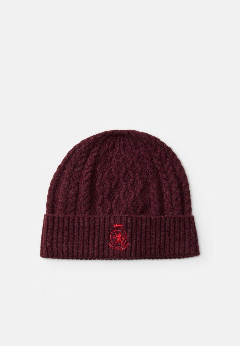 Bonnet bordeaux en maille torsadée avec revers côtelé arborant un écusson rouge brodé et le mot « HILFIGER » sur fond blanc.
