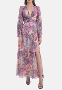 Maxi dress in sheer, floral fabric featuring pink, purple, and gold colors, long sleeves, v-neck, and leg slit. Adjustable waist detail.