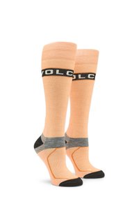 Calcetines hasta la rodilla en durazno claro, con una banda negra con el logo "VOLCOM", áreas acolchonadas grises y secciones reforzadas en el dedo del pie y el talón en negro.