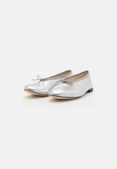 Silver metallic ballet flats with a smooth texture, rounded toes, and small bow detail on the front; flat black heels.