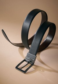 Black textured leather belt with a rectangular metal buckle, featuring a smooth finish and adjustment holes along the strap.