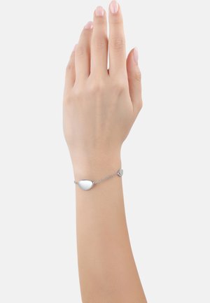Bracciale in argento con ciondolo a forma di goccia e piccolo accento rotondo, collegati da una delicata catena, indossato su un polso. Superficie liscia e riflettente.